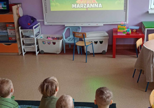 Dzieci poznają tradycje związaną z topieniem lub paleniem marzanny oglądając film edukacyjny na tablicy multimedialnej