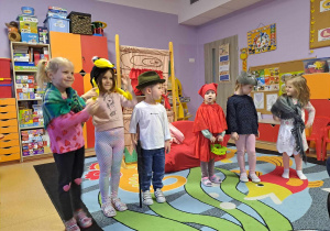 Dzieci odgrywające role w bajce Czerwony Kapturek pozują do zdjęcia w przebraniach