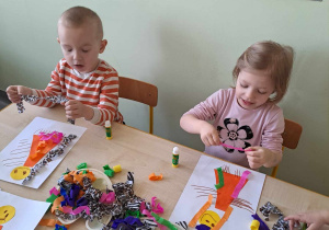 Dzieci dekorują marzannę za pomocą bibuły