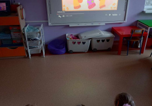 Dzieci oglądają film edukacyjny na tablicy multimedialnej na temat Dnia Kolorowej Skarpetki