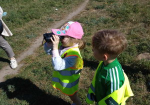 Dziewczynka obserwuje przez lornetkę ptaki na drzewie