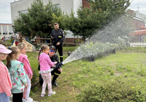 Dzieci leją wodą z węża strażackiego