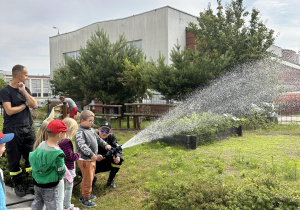 Dzieci leją wodą z węża strażackiego