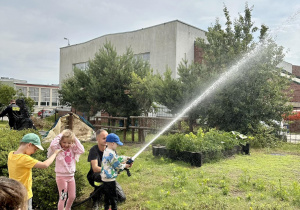 Dzieci leją wodą z węża strażackiego