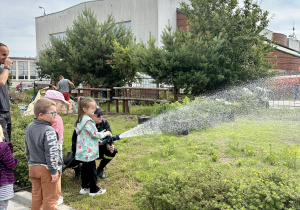 Dzieci leją wodą z węża strażackiego