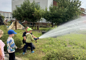 Dzieci leją wodą z węża strażackiego