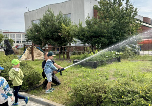 Dzieci leją wodą z węża strażackiego