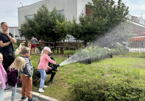 Dzieci leją wodą z węża strażackiego