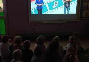 Dzieci oglądają film edukacyjny na tablicy multimedialnej o rodzajach przemocy