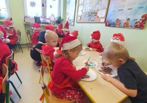 Dzieci siedzą przy stolikach i malują pierniki