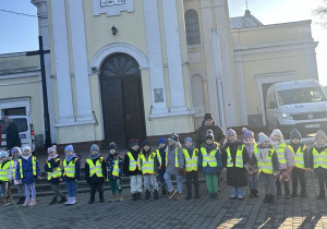 Dzieci wraz z wychowawczynią pozują do wspólnego zdjęcia przy Kościele Świętego Józefa