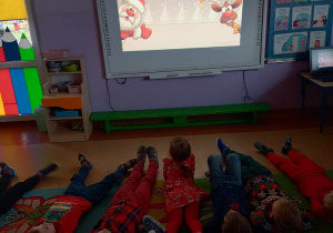 Dzieci oglądają na tablicy multimedialnej film edukacyjny na temat zwyczajów Mikołajkowych