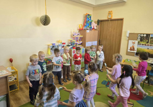 Dziewczynki podchodzą do stojących w szeregu chłopców i wręczają im bezowe kwiatki.