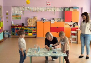 Chłopiec wlewa do naczynia z olejem zabarwioną barwnikiem spożywczym na niebiesko wodę