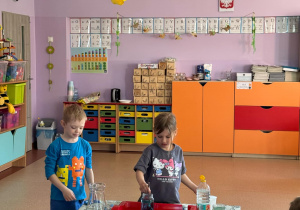 Dziewczynka miesza w szklanym pojemniku wodę z dodatkiem niebieskiego barwnika spozywczego