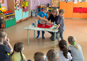 Chłopiec wlewa wodę do szklanego pojemnika