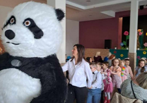 Dzieci wraz z nauczycielkami poruszają się w rytm muzyki za Misiek Pandą