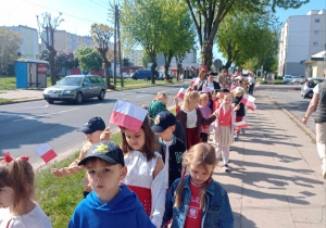 Dzieci z flagami w rękach spacerują ulicami osiedla w rytm poloneza